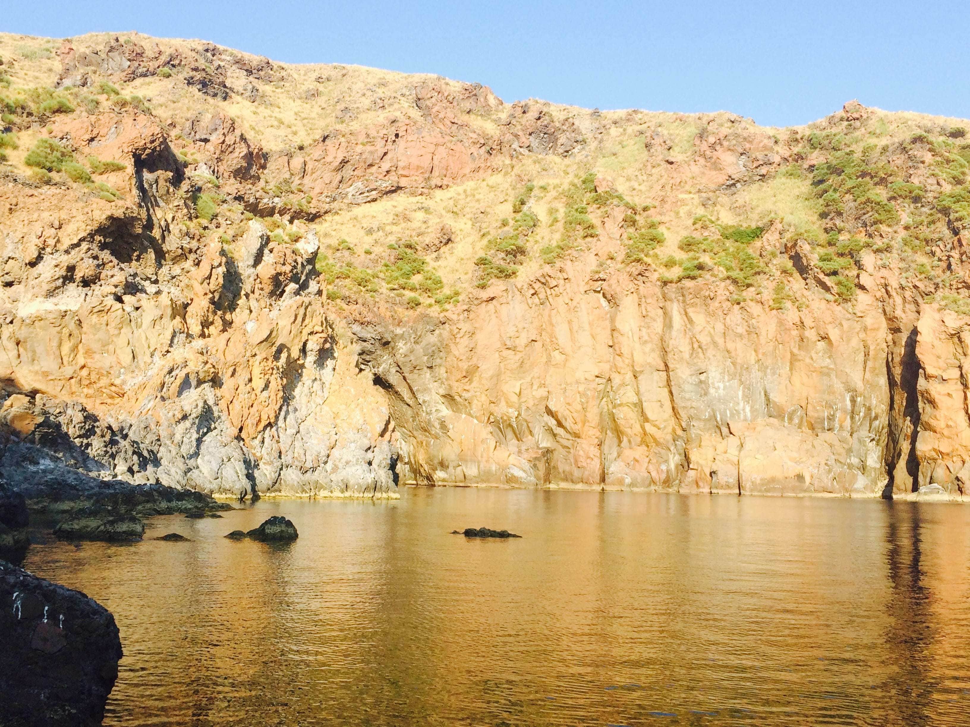 Paesaggio naturale con una scogliera rocciosa e una superficie d'acqua calma.