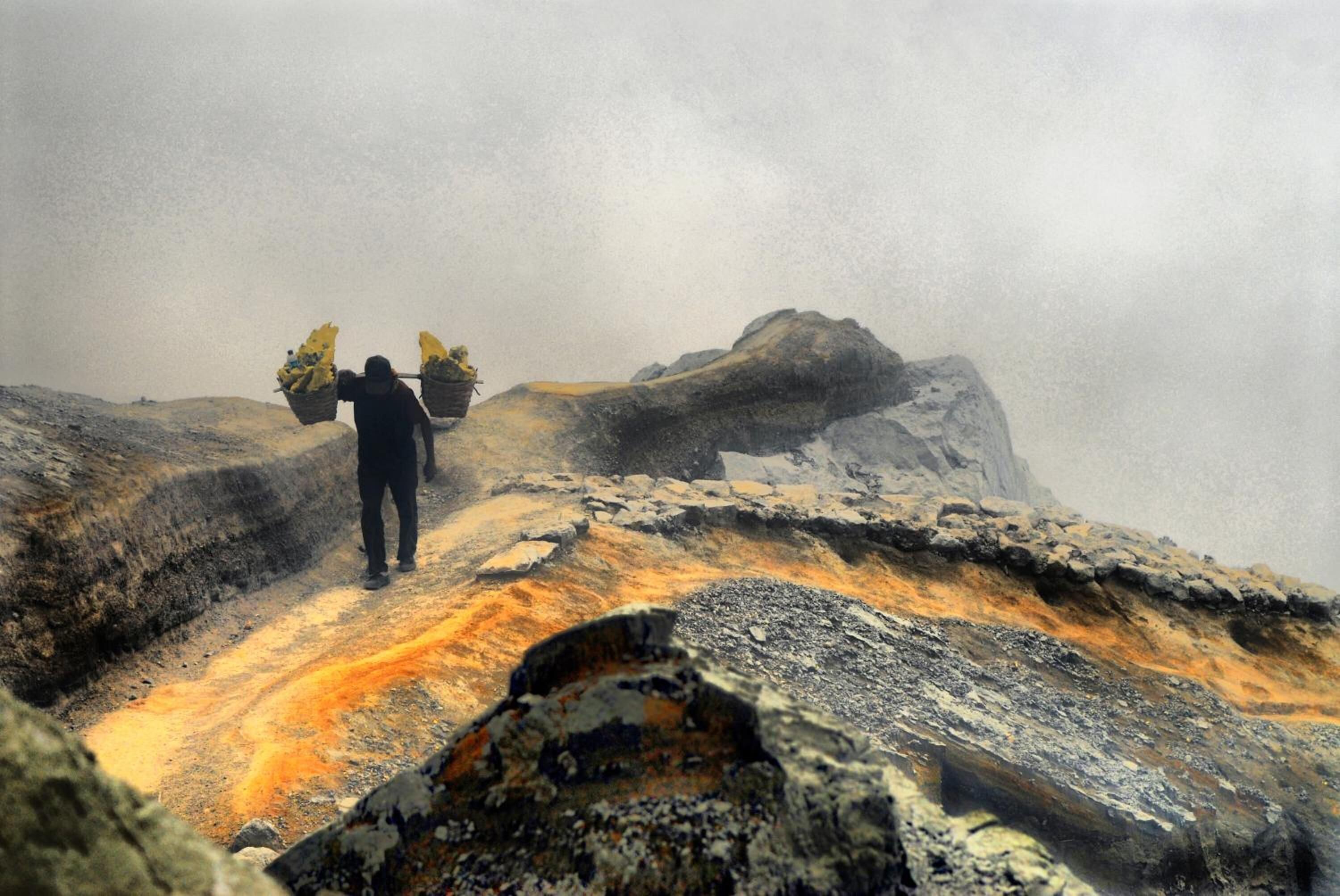 A rugged outdoor landscape with a person carrying a basket on their back.