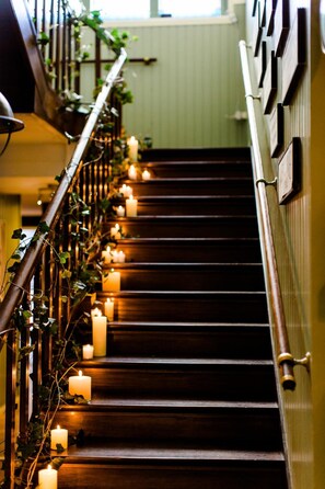 A wooden staircase with a railing decorated with greenery and lit by candles. - Parkhotel Hugo de Vries (Lunteren)