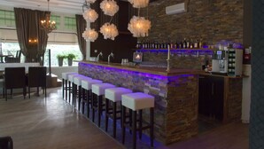 Una zona de bar con mostrador de piedra, taburetes y una lámpara moderna.