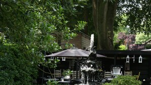 Un jardín con una fuente, una mesa y un edificio al fondo.