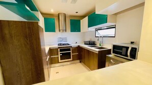 Een moderne keuken met een gasfornuis, magnetron en een inbouwoven.