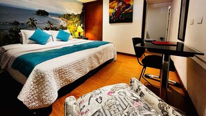 Een hotelkamer met een bed, een bureau, een stoel en een schilderij aan de muur.