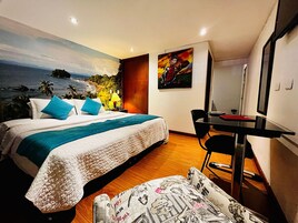 Una habitación de hotel con una cama, un escritorio, una silla y un cuadro en la pared.
