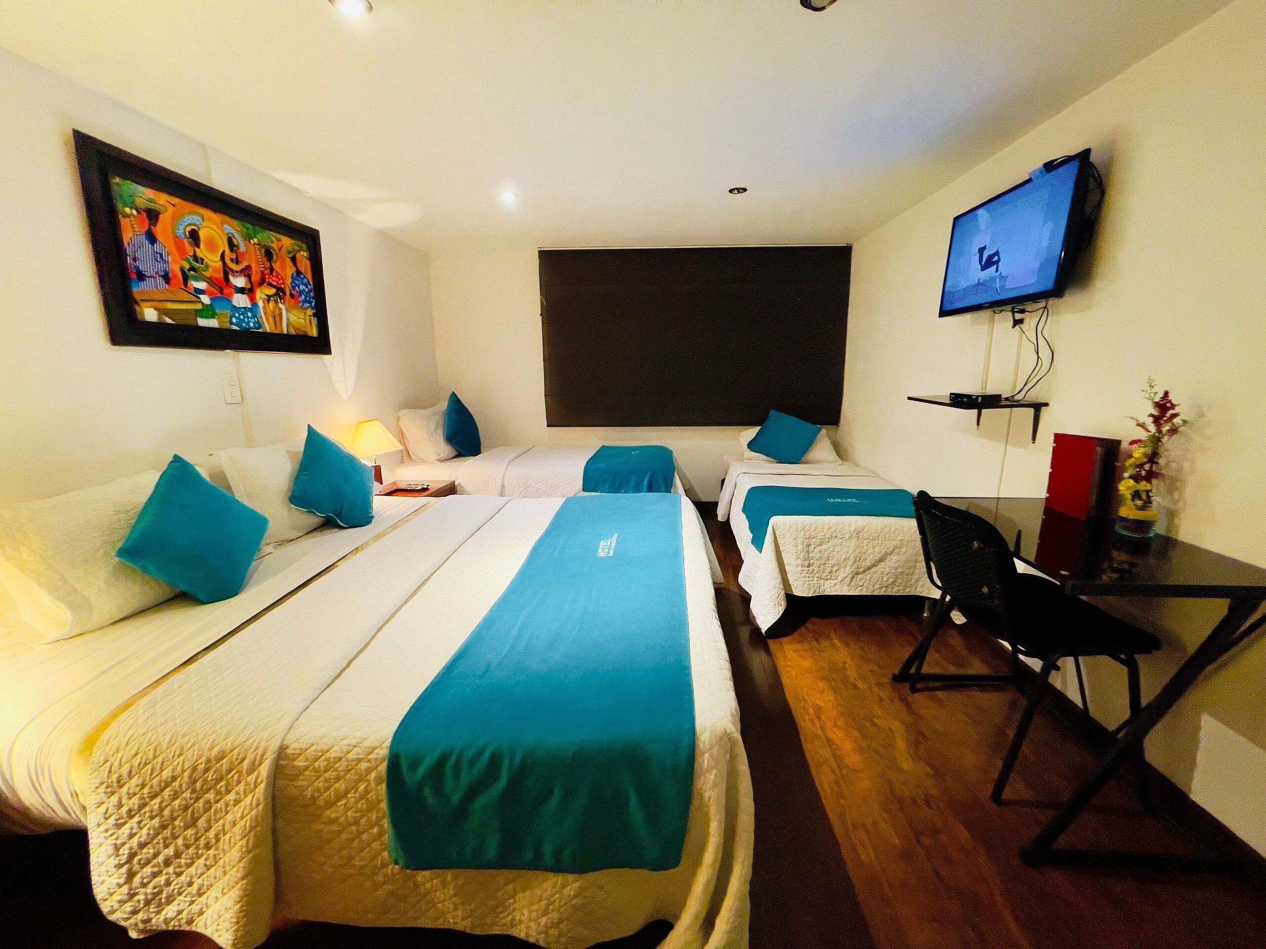 Een hotelkamer met twee bedden, een bureau, een stoel, een televisie en een schilderij aan de muur.