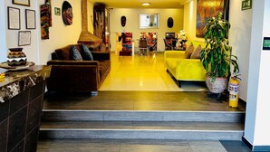 Een moderne hotel lobby met een receptiebalie, een zithoek en kunstwerken aan de muren.