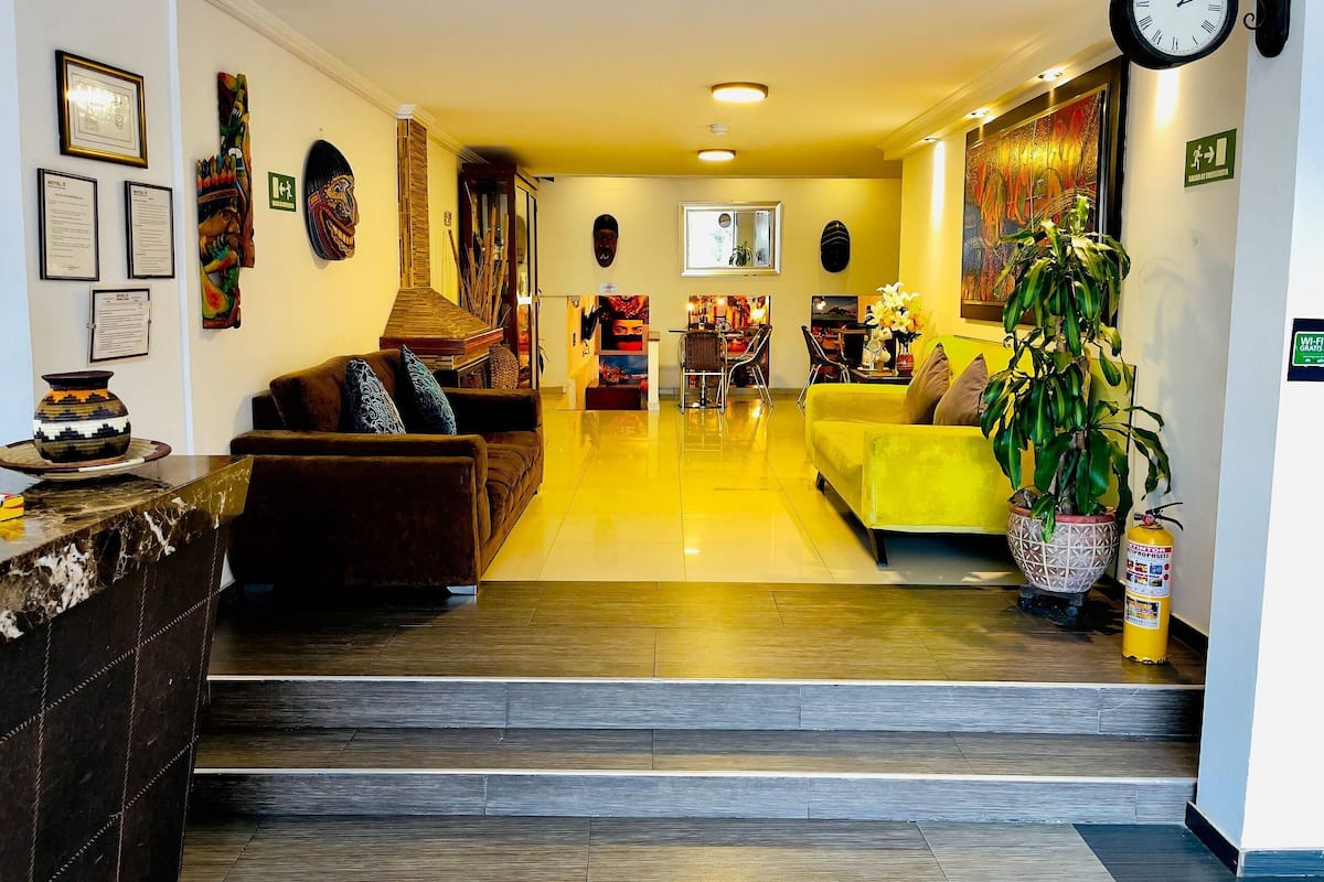 A modern hotel lobby with a reception desk, seating area, and artwork on the walls.