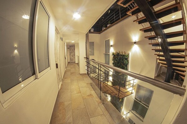Un intérieur moderne avec un escalier en colimaçon, une balustrade en verre et une vue sur le niveau inférieur.