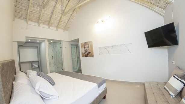 Um quarto com uma cama, televisão, sofá e obras de arte nas paredes.