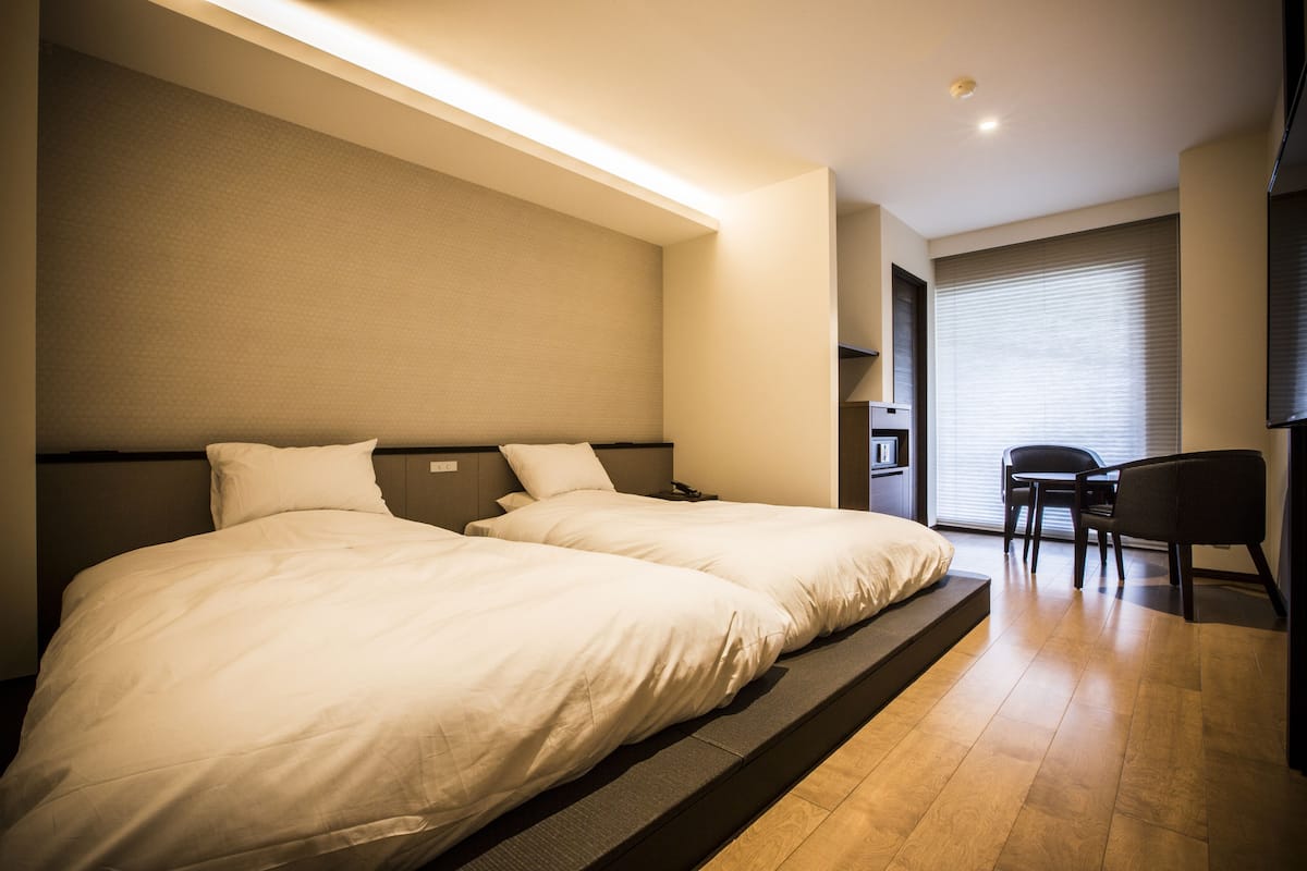 Une chambre d’hôtel avec deux lits, un bureau et une chaise.