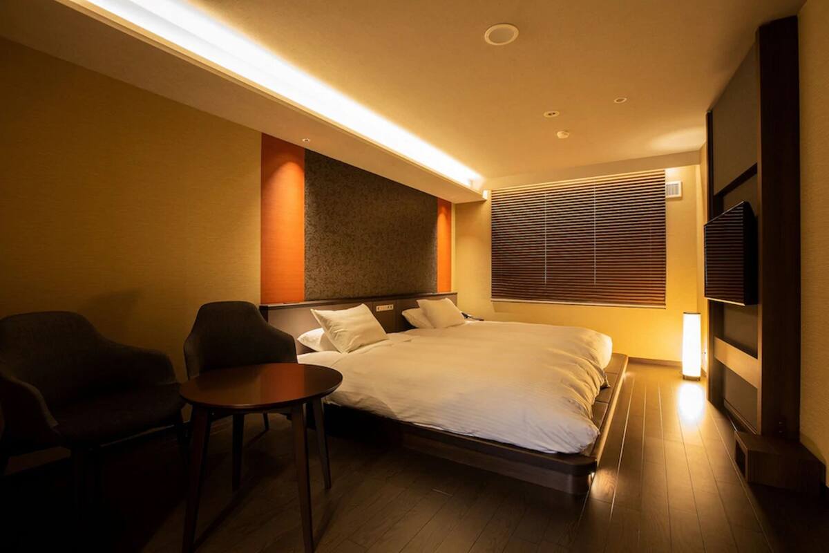 Une chambre d’hôtel moderne équipée d’un grand lit, d’un bureau, de deux chaises et d’une télévision.