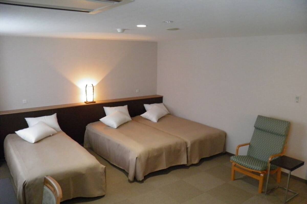 Une chambre d’hôtel avec deux lits simples, une chaise et une petite table.