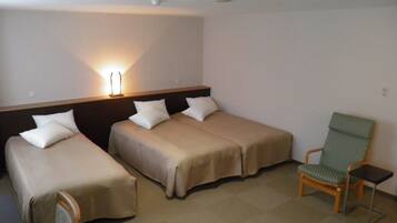 A hotel room with two single beds, a chair, and a small table.
