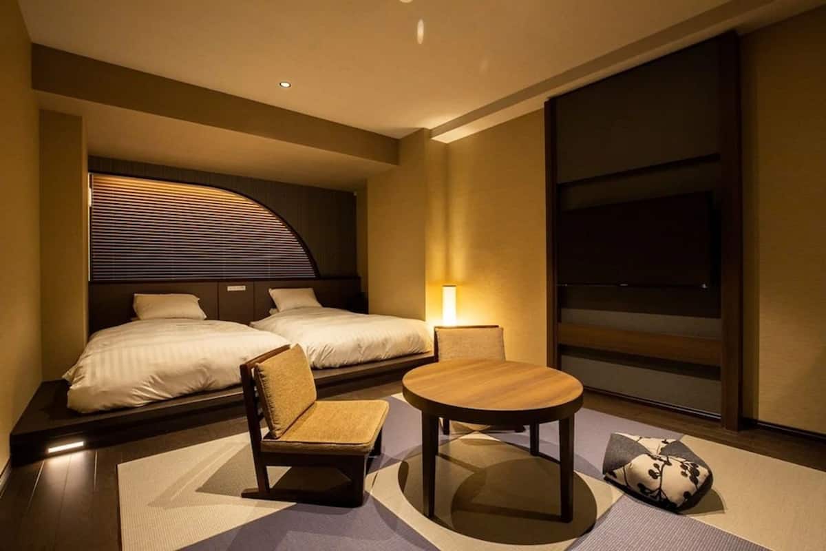 Une chambre d’hôtel avec deux lits, une petite table, une chaise et un téléviseur.
