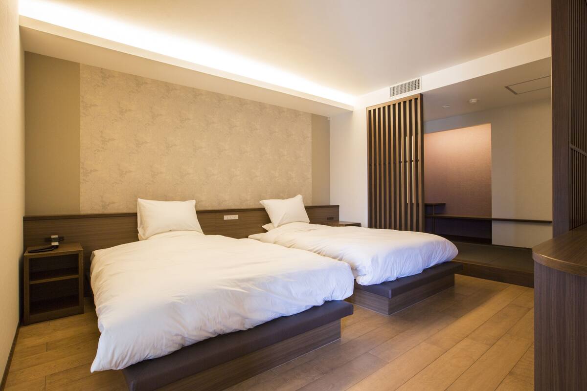 Une chambre d’hôtel avec deux lits, des têtes de lit en bois et un grand miroir.