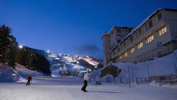 A snow-covered ski slope at dusk with a building on the right. - Yumoto Niseko Prince Hotel Hirafutei (Kutchan)