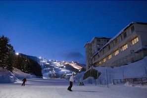 A snow-covered ski slope at dusk with a building on the right. - Yumoto Niseko Prince Hotel Hirafutei (Kutchan)