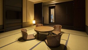 A hotel room with a round table, four chairs, a TV, a lamp, and a sliding door. - Yumoto Niseko Prince Hotel Hirafutei (Kutchan)