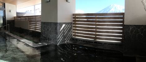 A spa area with a stone wall, a water feature, and a view of a mountain.