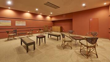 A conference room with a carpeted floor, wooden furniture, and a wooden cabinet.