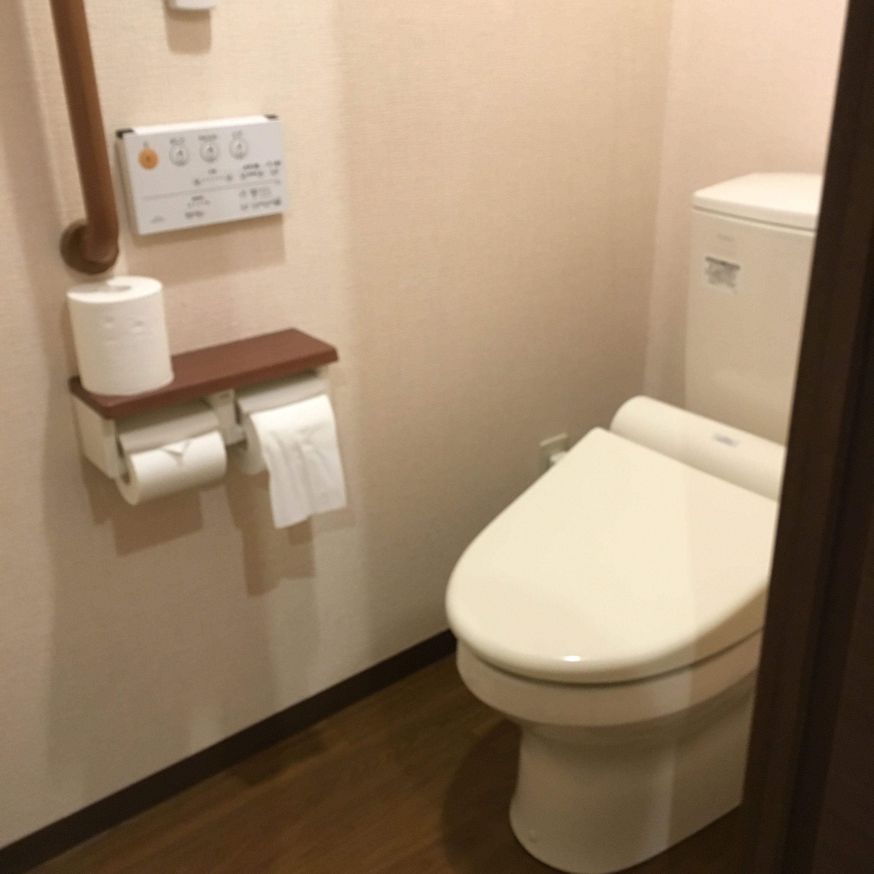 Un baño de hotel estándar con inodoro, dispensador de toallas de papel y secador de manos.