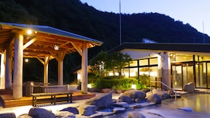 Un edificio con un espacio exterior techado, piscina y montañas al fondo.