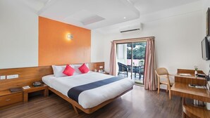 Quarto de hotel com uma cama grande, uma escrivaninha e vista para o exterior.