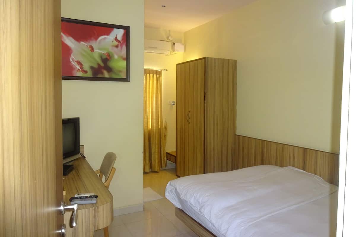 Une chambre d’hôtel comprenant un lit, un bureau avec une chaise, une télévision et une armoire.