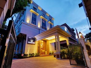 A hotel entrance with a covered walkway, a signboard, and a gated entrance. - The Rialto Hotel Bangalore (Bengaluru)
