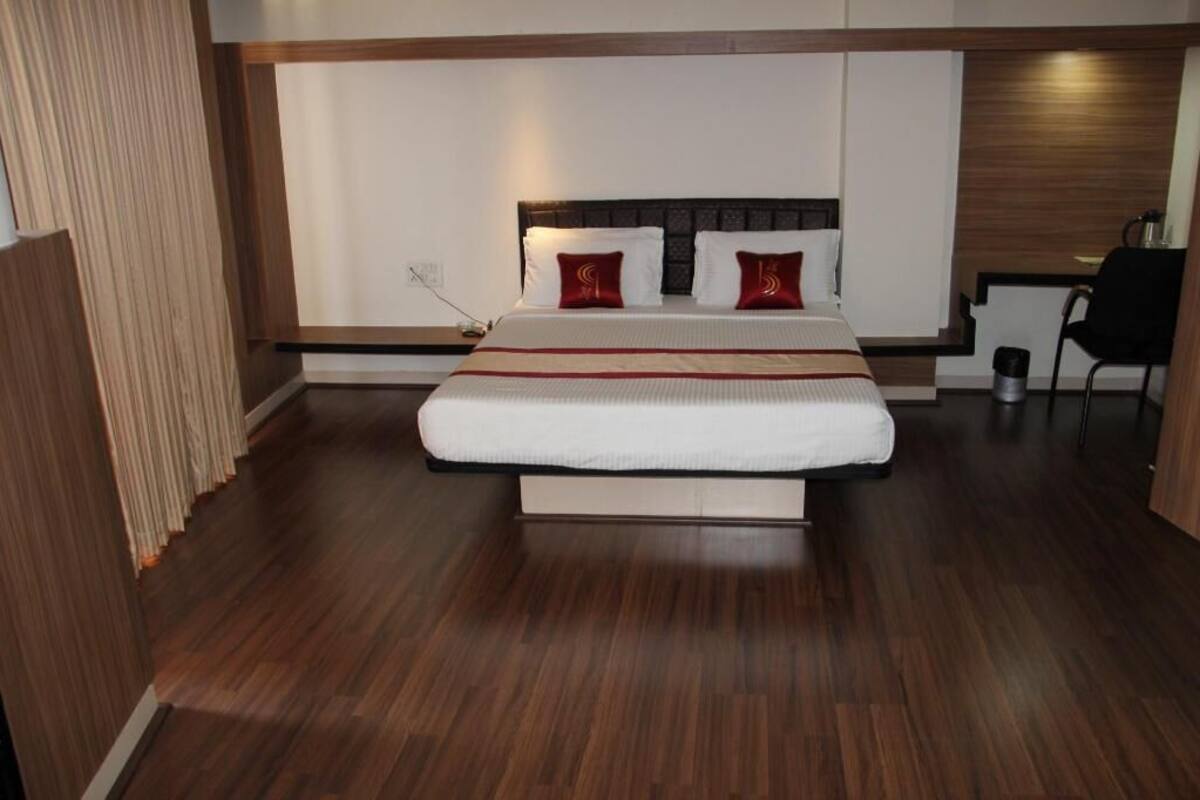 A modern hotel room with a large bed, a desk, and a chair.