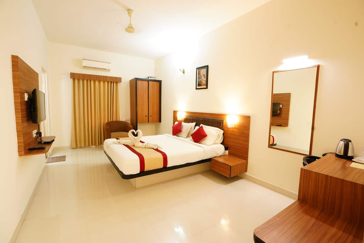 A modern hotel room with a bed, bedside table, mirror, and a small desk with a kettle.
