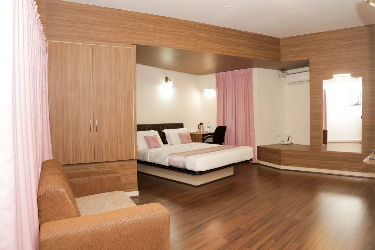 A modern bedroom with a wooden wardrobe, a bed with a headboard, a desk, and a mirror.