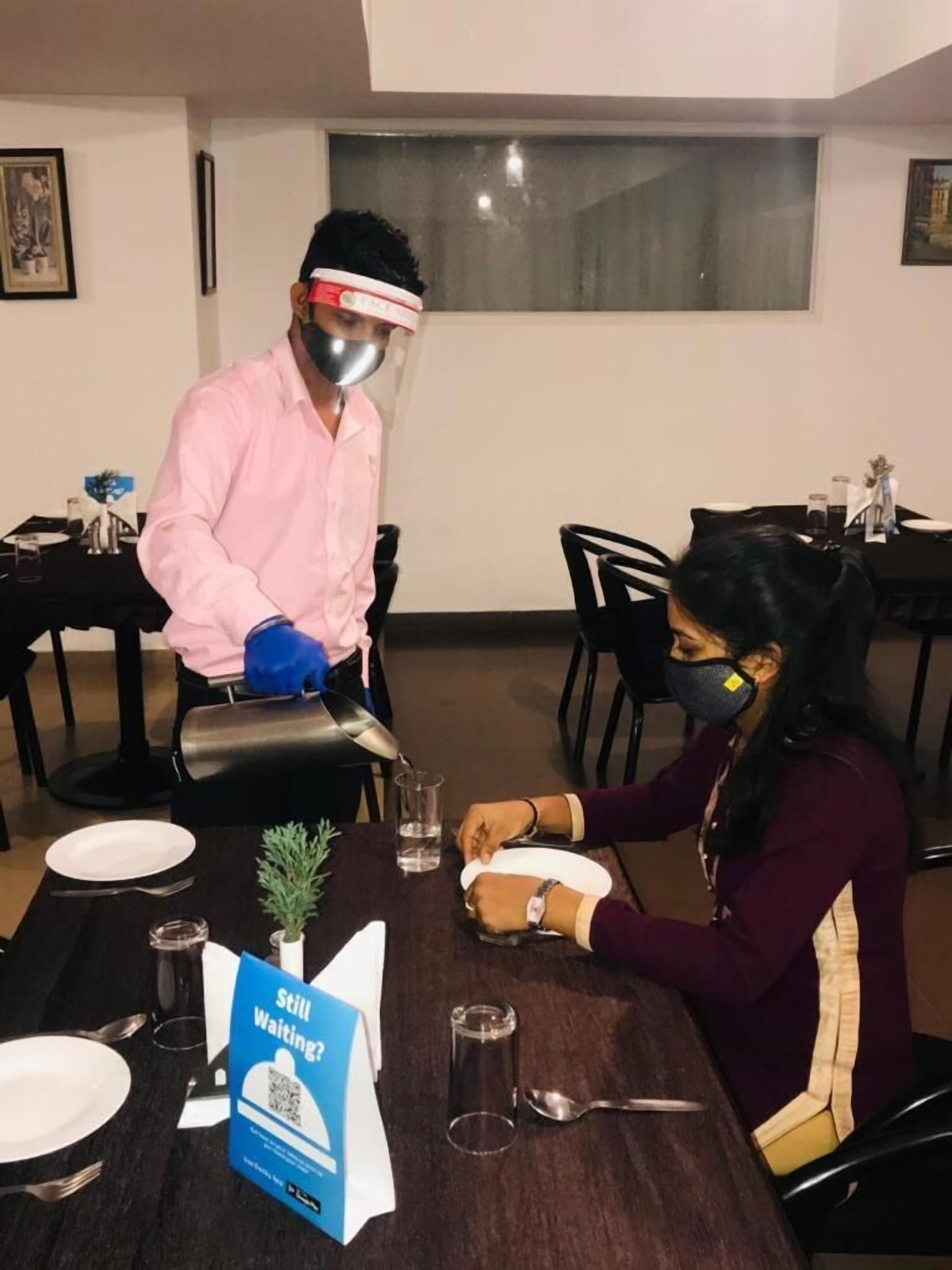 Un comedor con una mesa dispuesta para dos personas, un menú y un cartel con código QR.