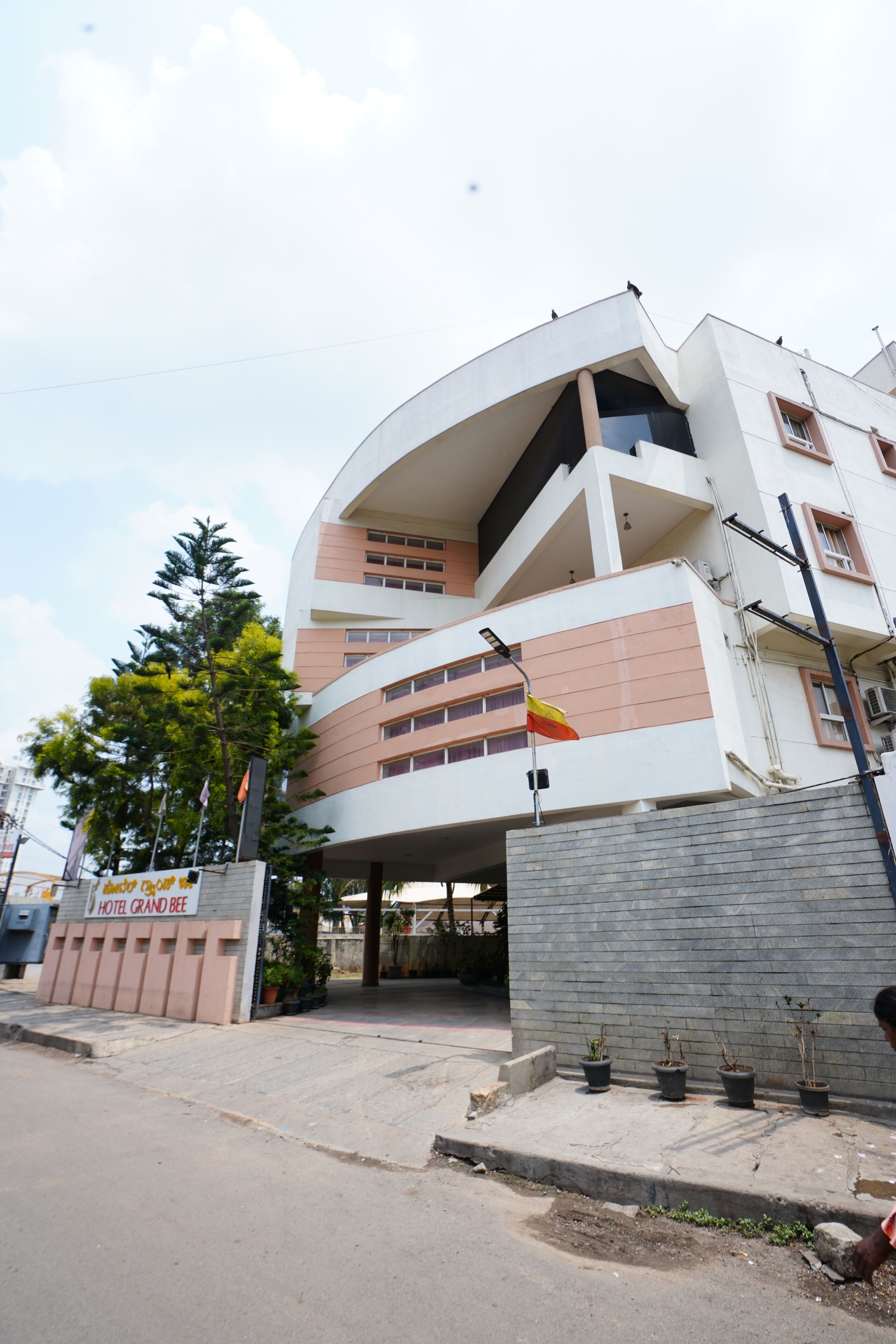 A modern hotel with a curved facade, multiple balconies, and a flag.
