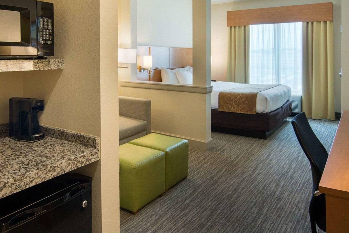 Ein Hotelzimmer mit Bett, Schreibtisch, Mikrowelle, Kaffeemaschine und einer Sitzecke.