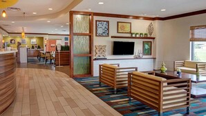 A hotel lobby with a reception desk, seating area, and a TV mounted on the wall. - Comfort Suites Bossier City - Shreveport (Bossier City)