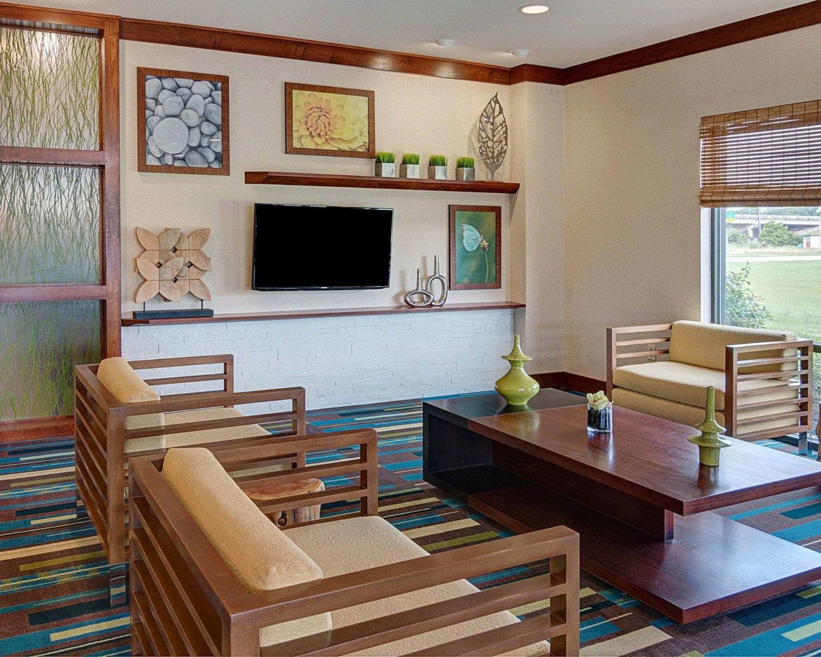 A modern living room with a flat-screen TV, wooden furniture, and decorative wall art.