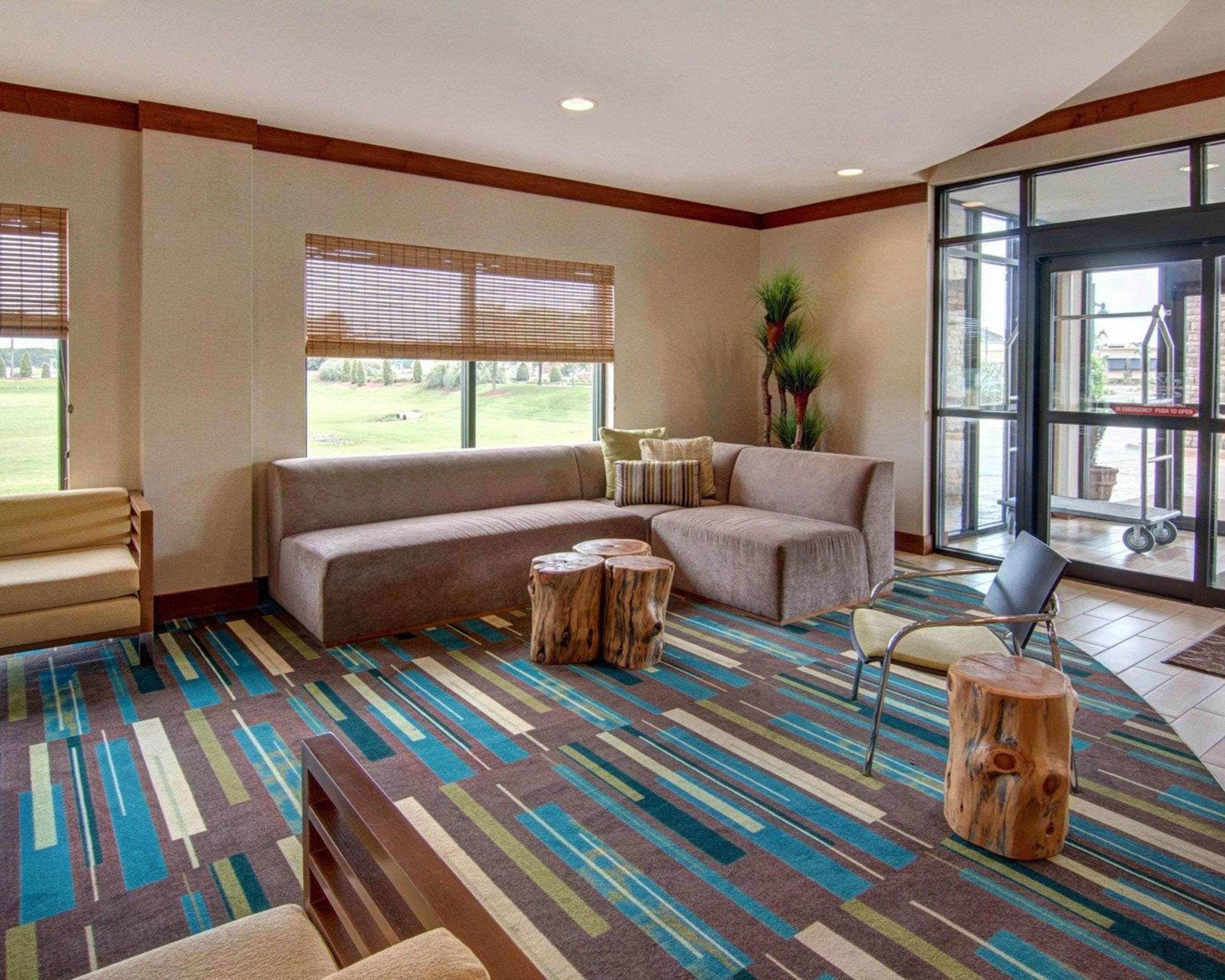 Un espacio lounge moderno con un sofá modular, una mesa de centro de madera y una alfombra estampada.