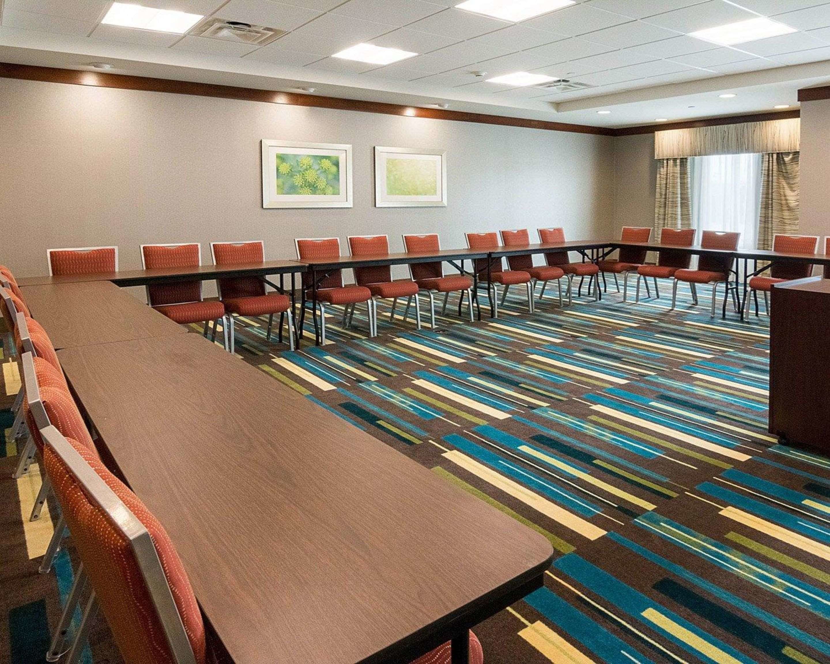 A conference room with a long table and chairs, a patterned carpet, and two framed pictures on the wall.
