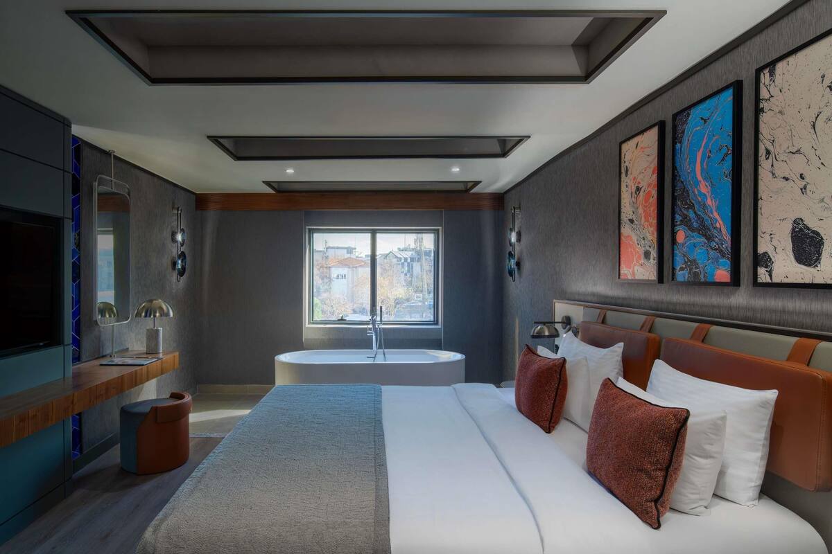 Een moderne hotelkamer met een groot bed, een zithoek, een badkuip en een televisie.