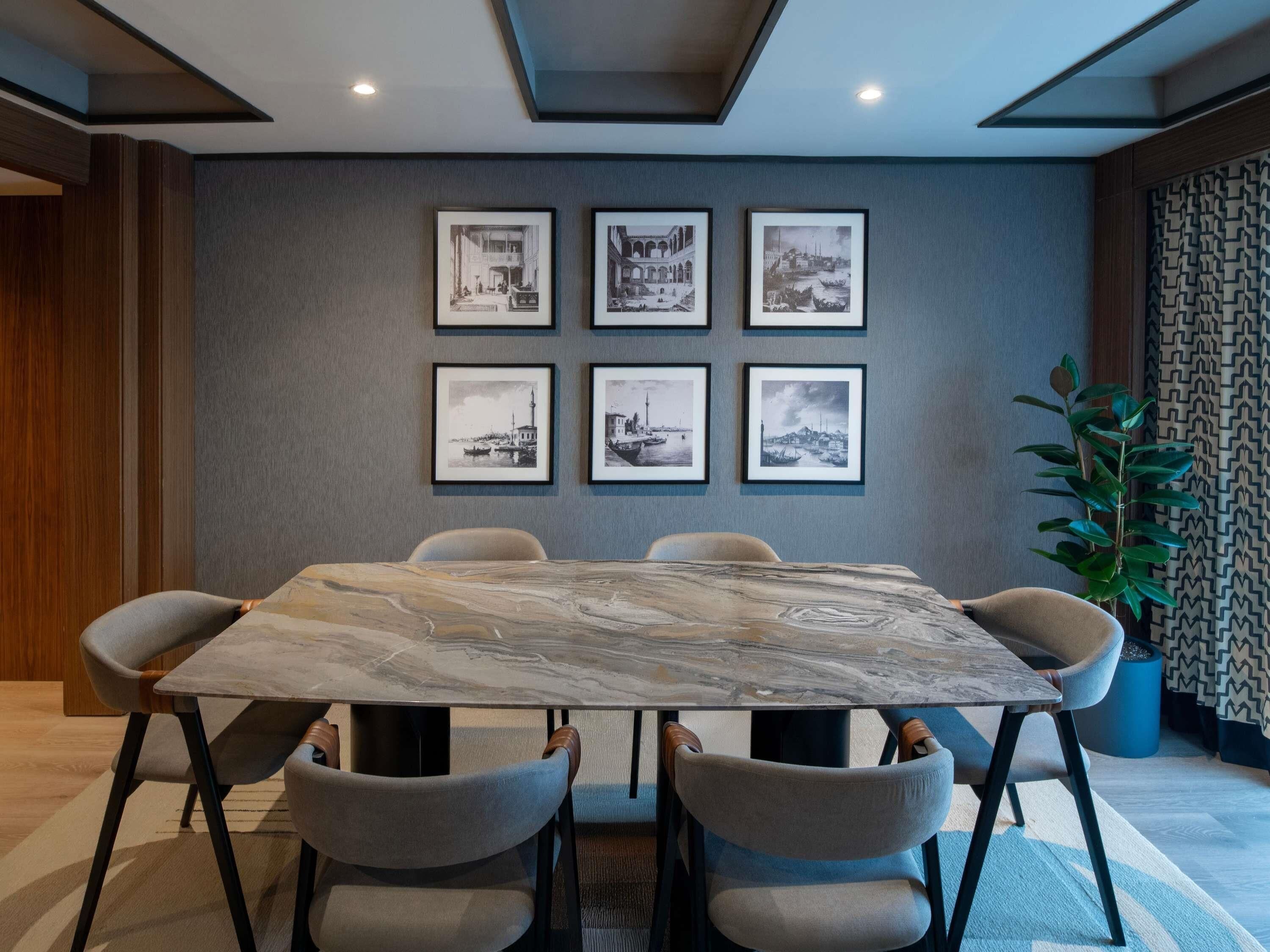 A conference room with a marble table, six chairs, and six framed black-and-white cityscape photographs on the wall.