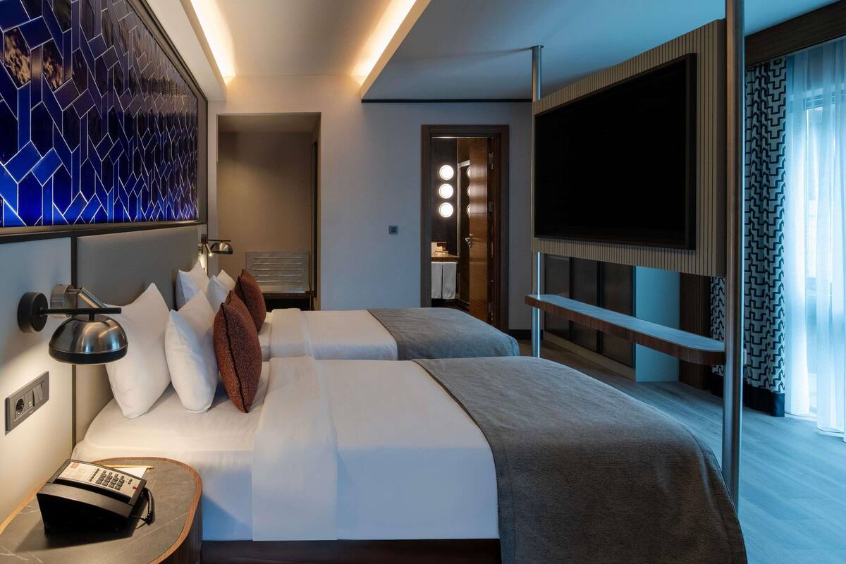 Een hotelkamer met een bed, nachtkastje, televisie en een spiegel.