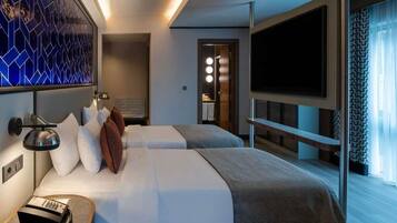 Une chambre d’hôtel moderne avec deux lits, une télévision, un bureau avec une lampe et un mur décoratif.