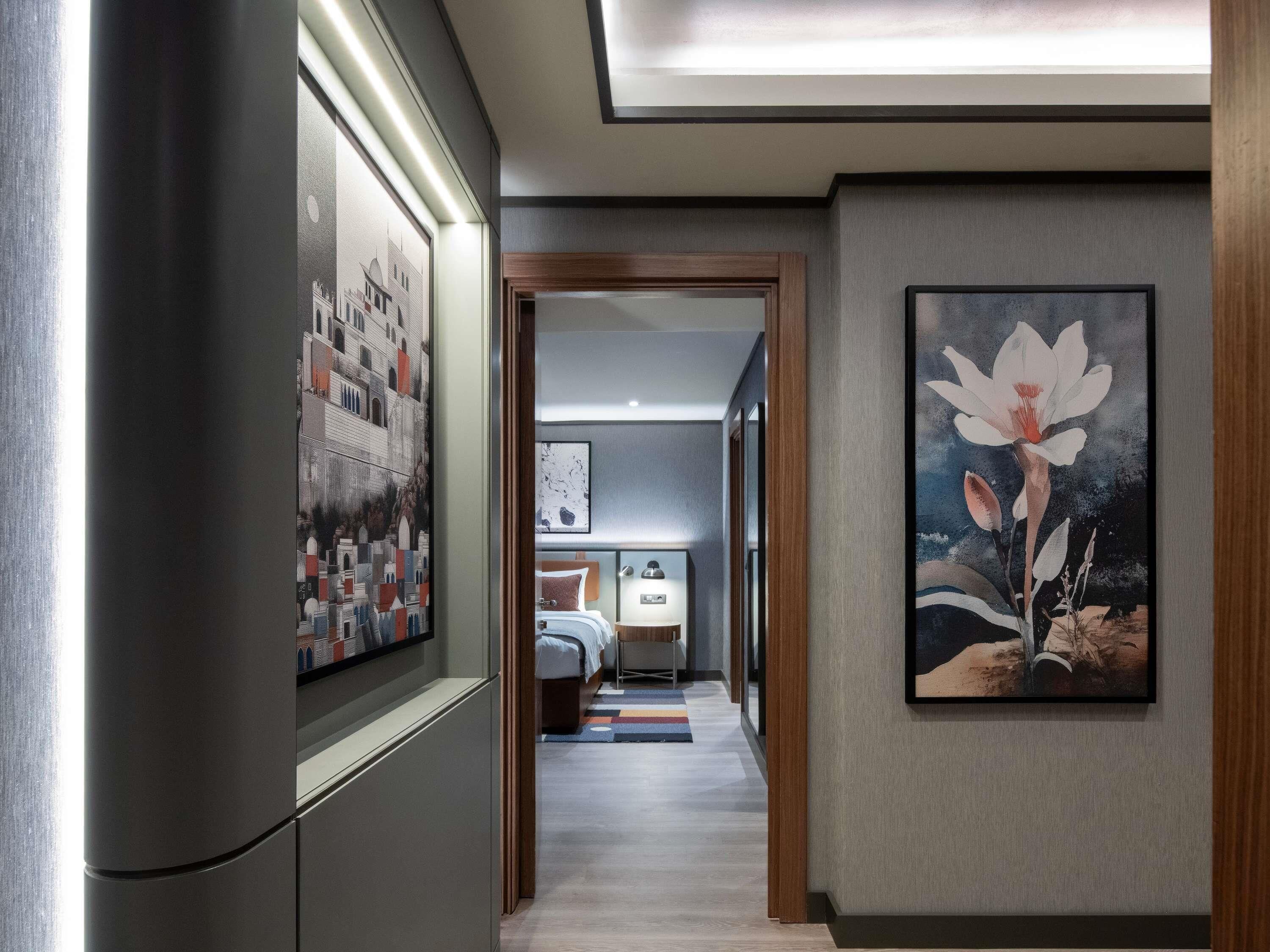 A hallway with a bed, a nightstand, and a painting of a flower.