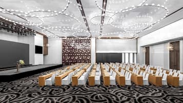 Un salón de conferencias con filas de sillas, un escenario y una alfombra estampada.