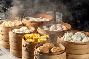 A variety of steamed buns in bamboo steamers, including corn and meat varieties.