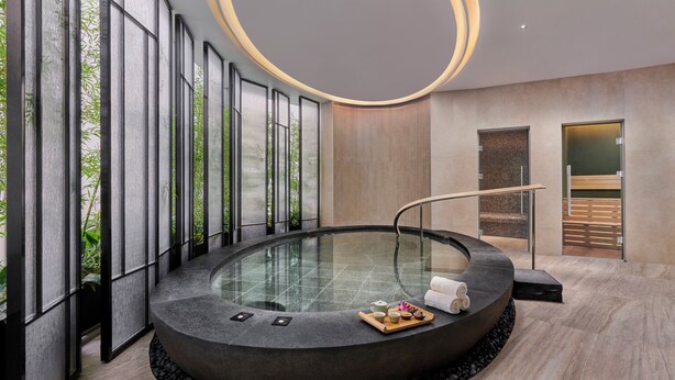 Un spa moderno con una bañera de hidromasaje circular, amplios ventanales y un diseño minimalista.