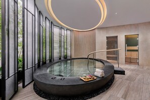 Un spa moderne doté d’un bain à remous circulaire, de grandes fenêtres et d’un design minimaliste.
