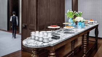 A marble-topped buffet table with white cups and saucers, a vase with white flowers, and a blue vase with a dragon design.