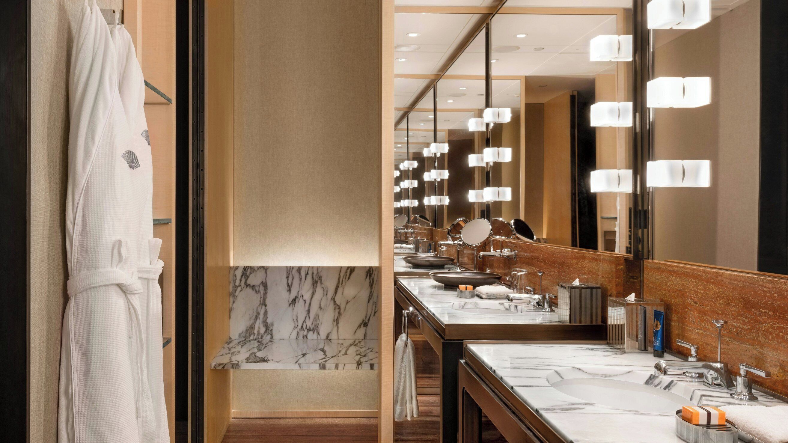 A hotel bathroom with a marble vanity, multiple sinks, and a large mirror.
